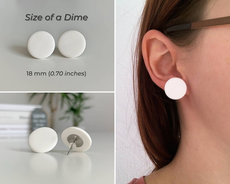Op de afbeelding: Een paar witte ronde oorbel studs, elk met een diameter van 18 mm (0,70 inch). De oorbellen worden getoond op een wit oppervlak en op het oor van een persoon.