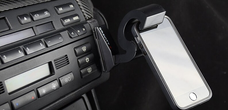 May include: A black car phone mount with the word "GRAVITY" printed on it. A smartphone is attached to the mount.