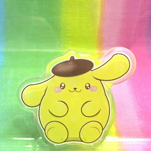 以下が含まれることがあります： 茶色のベレー帽とピンクの頬をした黄色の漫画のキャラクター。キャラクターは大きな耳を持ち、白で縁取られています。背景はピンク、緑、黄色のグラデーションです。