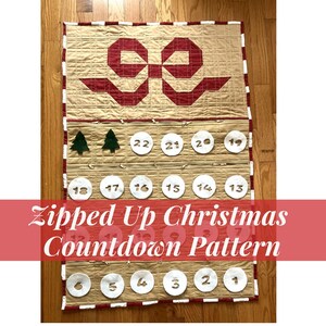 Peut inclure: Un patron de calendrier de l'Avent de Noël fait à la main avec 24 poches zippées. Le calendrier matelassé beige et rouge présente un grand motif de nœud, des cercles numérotés et des appliqués d'arbres de Noël. Le texte sur le calendrier indique "Zipped Up Christmas Countdown Pattern."