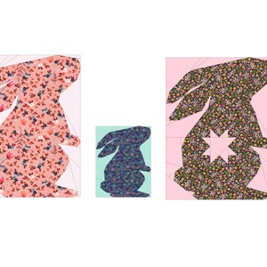 May include: Three paper cut-out bunnies with floral patterns. The largest bunny is pink with red and blue flowers, the middle bunny is blue with white and pink flowers, and the smallest bunny is black with yellow and pink flowers.
