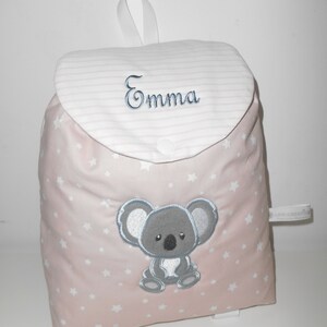 K&ouml;nnte beinhalten: Ein rosa Rucksack mit wei&szlig;en Sternen und einem gestickten grauen Koala auf der Vorderseite. Der Rucksack hat eine wei&szlig;e Klappe mit rosa Streifen und den Namen "Emma" darauf gestickt.
