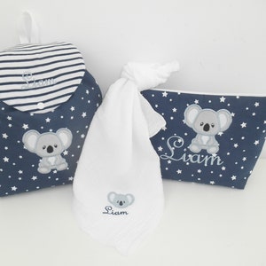 K&ouml;nnte beinhalten: Ein Set aus drei Babyartikeln in einem blau-wei&szlig;en Sternenmuster. Das Set beinhaltet eine Wickeltasche, ein Waschlappen und eine Kosmetiktasche. Jedes Teil ist mit einem grauen Koalab&auml;ren und dem Namen "Liam" bestickt.