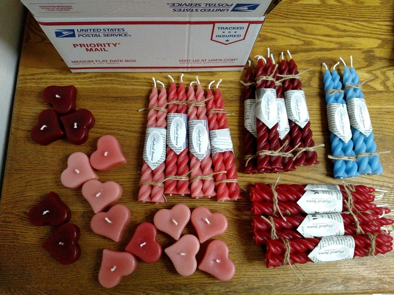 May include: Assortment of heart-shaped and twisted candles in red, pink, and blue. The candles are packaged in bundles and tied with twine. The image also includes a USPS Priority Mail box.