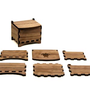 May include: A wooden box with a lid, assembled and unassembled pieces. The box is made of light brown wood with a turtle design on one of the pieces. The box is approximately 3 inches wide and 3 inches tall.