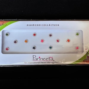 May include: A white box with a green border containing 10 colorful round bindi stickers. The box says "Diamond Collection" and "Parineeti Bindi An International Award Winning Product".