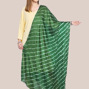 May include: A green and white striped scarf is draped over a person wearing a yellow top. The scarf has a diagonal pattern of white stripes against a green background. The person is wearing a yellow top with a V-neck.