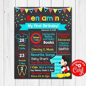 May include: A chalkboard style first birthday sign featuring a Mickey Mouse theme. The sign is decorated with red, yellow, and blue polka dots and includes the name "Benjamin" and details about the child's first year, including height, weight, favorite foods, and songs. The sign also includes a personalized message that says "Personalize with Coril".