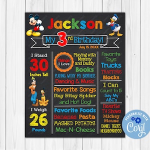 Op de afbeelding: Een zwart krijtbord verjaardagsteken met kleurrijke tekst en illustraties van Mickey Mouse, Donald Duck en Goofy. Het bord zegt "Jackson's 3rd Birthday!" en bevat details zoals lengte, gewicht, favoriete dingen en favoriete etenswaren. Het bord is gepersonaliseerd met de naam "Coril".