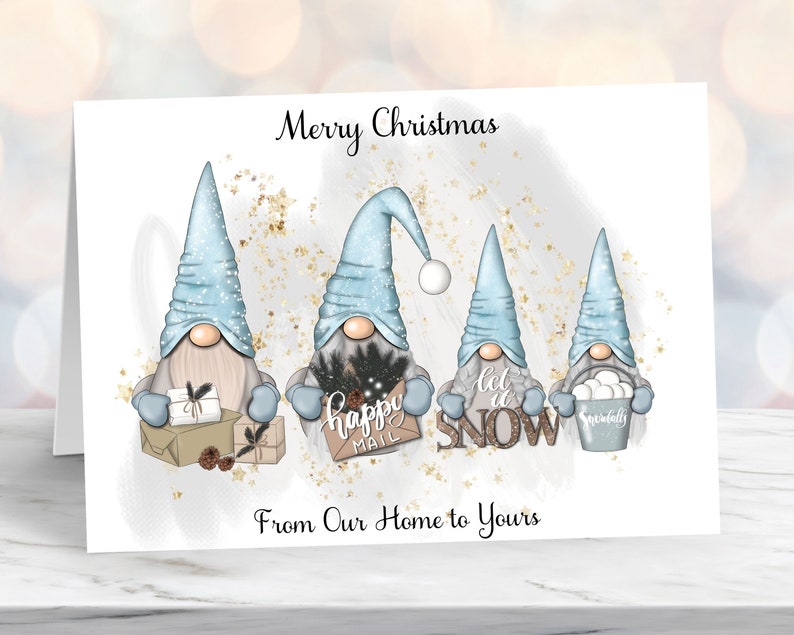 May include: A Christmas card featuring three gnomes with blue hats and white beards. The gnomes are holding gifts and signs that say "Happy Mail", "Let it Snow", and "Snowballs". The card has a white background with gold glitter and the text "Merry Christmas" and "From Our Home to Yours".
