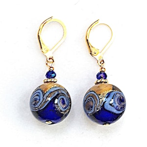 May include: Gold dangle earrings with blue and gold glass beads. The beads have a swirling pattern.