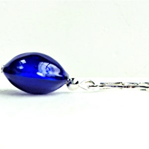Pu&ograve; includere: Un orecchino a goccia di vetro blu scuro con un gancio d'argento.