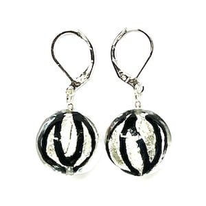 May include: A pair of silver dangle earrings with black and white striped glass spheres.