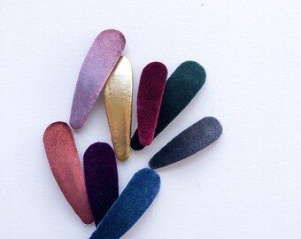 May include: Assortment of velvet hair clips in various colors, including purple, burgundy, dark blue, teal, and gold. The clips are all in the shape of a teardrop.