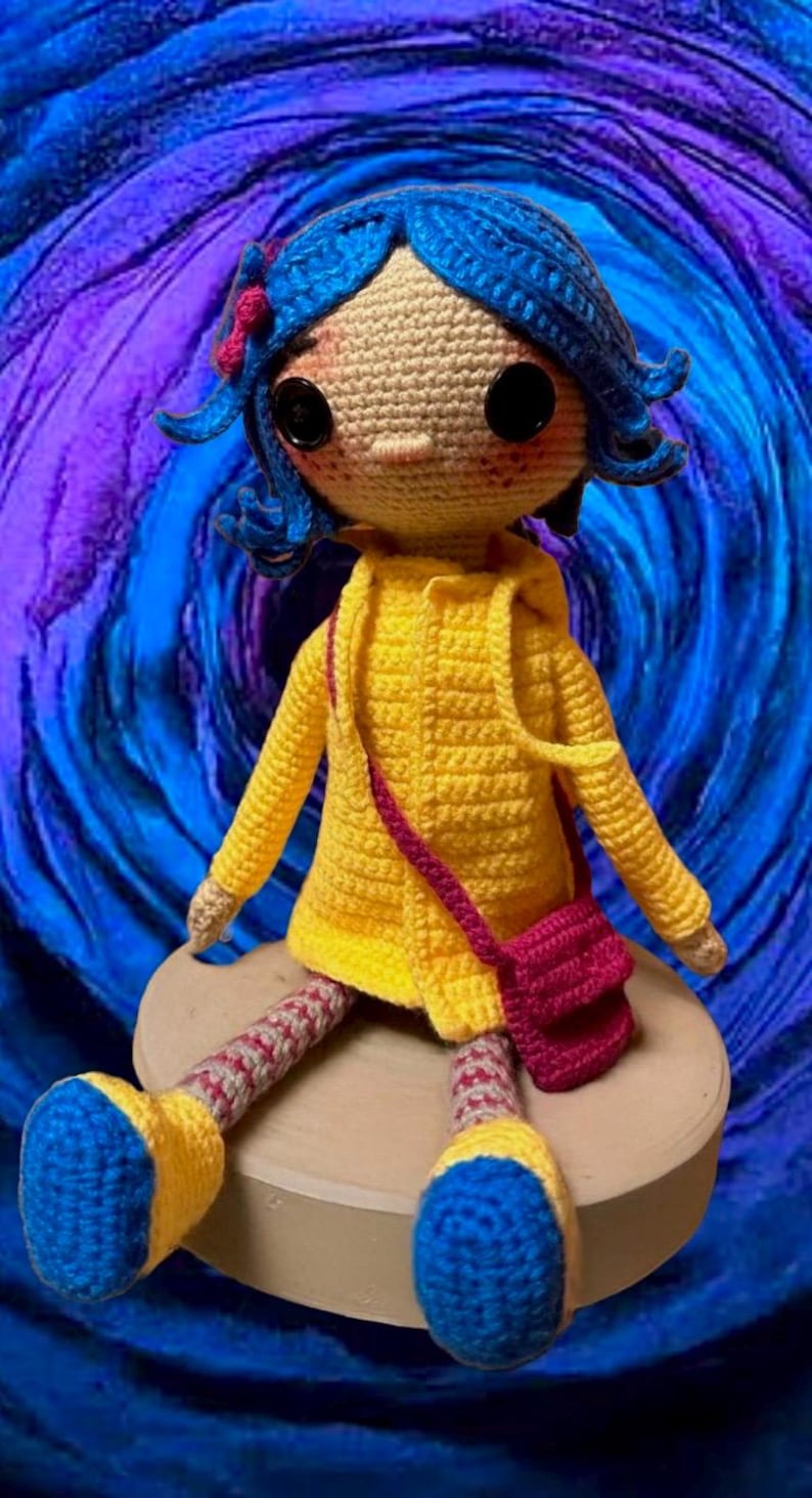 May include: A crocheted doll with blue hair, wearing a yellow raincoat and a pink bag, sitting on a round platform against a swirling purple and blue background.