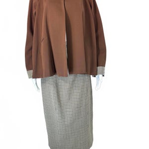 May include: A vintage brown jacket with a contrasting plaid collar and cuffs, paired with a matching plaid skirt. The jacket has a classic design with a wide collar and long sleeves. The skirt is a pencil style, creating a coordinated ensemble.