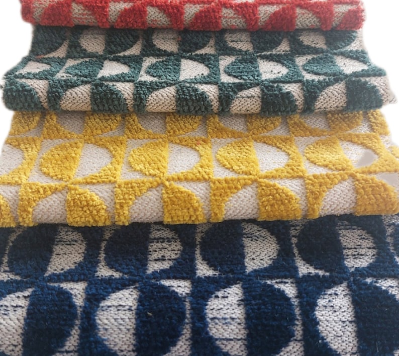 May include: Four different patterned rugs stacked on top of each other. The top rug is red, the second is green, the third is yellow, and the bottom rug is blue.