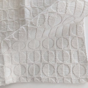 May include: White fabric with a textured pattern of repeating half circles. The fabric has a soft, plush feel.