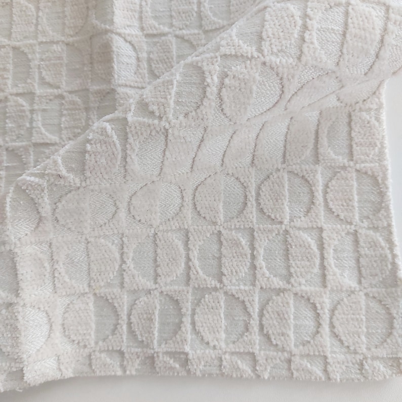 May include: White fabric with a textured pattern of repeating half circles. The fabric has a soft, plush feel.