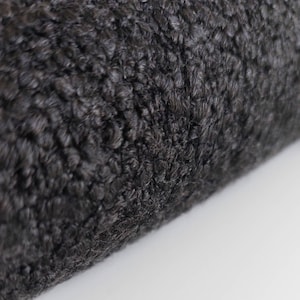 May include: Close-up of a black faux fur fabric with a soft, fluffy texture.