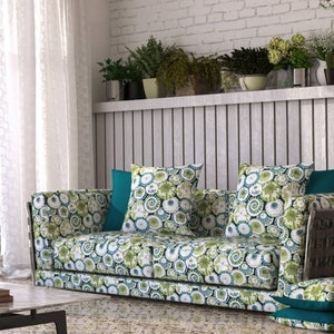 May include: A green and white patterned sofa with two green and white patterned throw pillows and a teal throw pillow. The sofa is in front of a white brick wall with a wooden shelf above it.