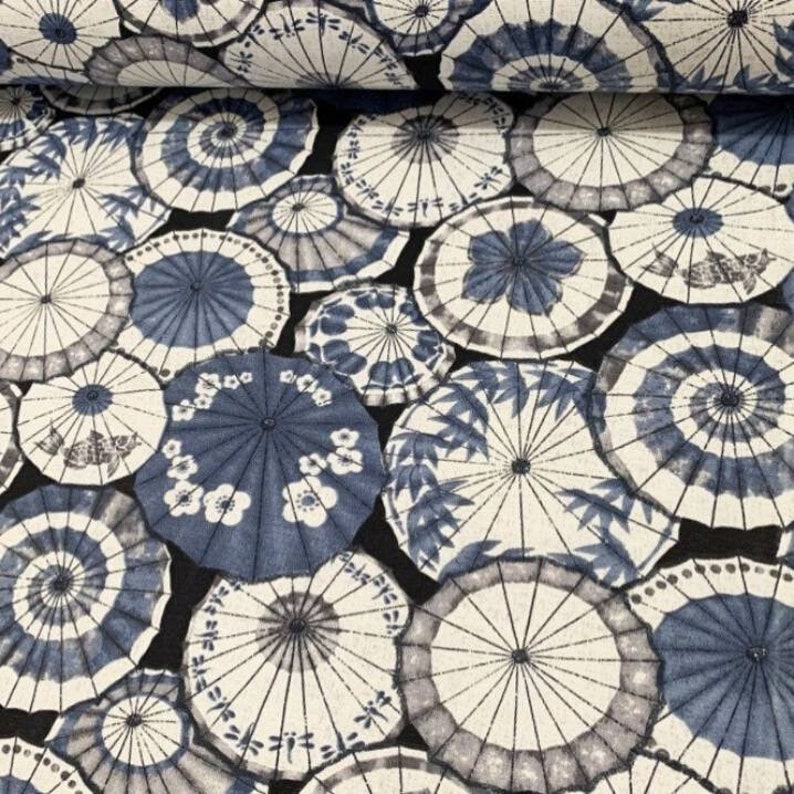 May include: Black fabric with a repeating pattern of blue and white Japanese umbrellas. The umbrellas are various sizes and have a traditional design.