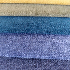 May include: A stack of six fabric swatches in various shades of blue, gray, yellow, and pink. The fabric has a soft, fuzzy texture.