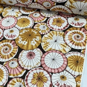 May include: A black fabric with a repeating pattern of white and gold umbrellas with pink accents. The umbrellas are arranged in a random pattern.