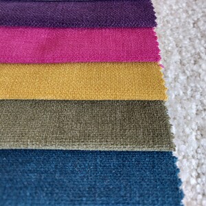 May include: Five fabric swatches in different colors and textures. The swatches are arranged in a stack, with the purple swatch on top and the blue swatch on the bottom. The swatches are all soft and plush.