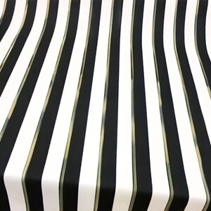 May include: A fabric with a bold striped pattern. Alternating vertical stripes of black and white dominate the design. Thin gold-colored lines separate the black and white stripes, adding a subtle accent to the overall aesthetic.