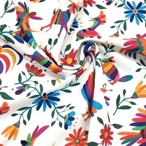 May include: White fabric with a colorful repeating pattern of stylized birds, flowers, and leaves. The pattern is reminiscent of Mexican folk art.
