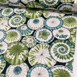 May include: A fabric with a repeating pattern of green and white umbrellas on a dark blue background.