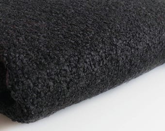 Op de afbeelding: Close-up van een zwarte, pluche stof met een zacht, getextureerd oppervlak.