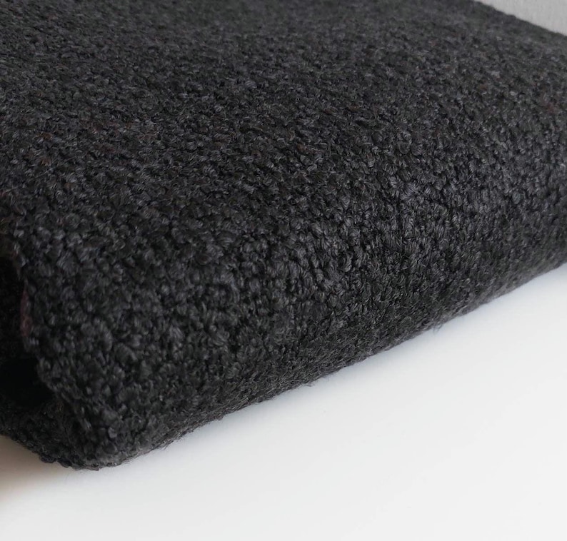 May include: Close-up of a black fuzzy fabric with a soft, textured surface.