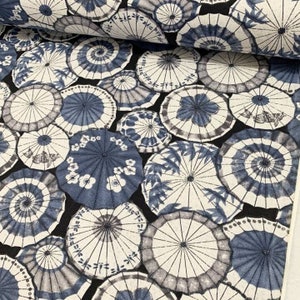 May include: A black fabric with a repeating pattern of blue and white umbrellas. The umbrellas are various sizes and have different designs, including floral and geometric patterns.