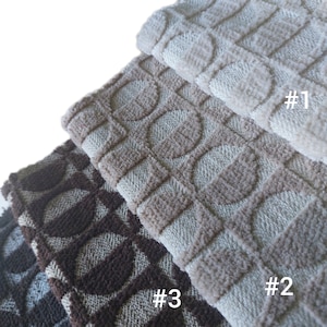 May include: Close-up of three textured fabric swatches in shades of beige, brown, and dark brown. Each swatch features a repeating pattern of circles within squares. The swatches are labeled #1, #2, and #3.