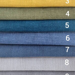 May include: A swatch card with 11 different fabric samples. The samples are arranged in a vertical row, with the numbers 1 through 11 printed next to each sample. The colors of the samples include purple, pink, yellow, green, blue, light blue, gray, dark gray, and black.