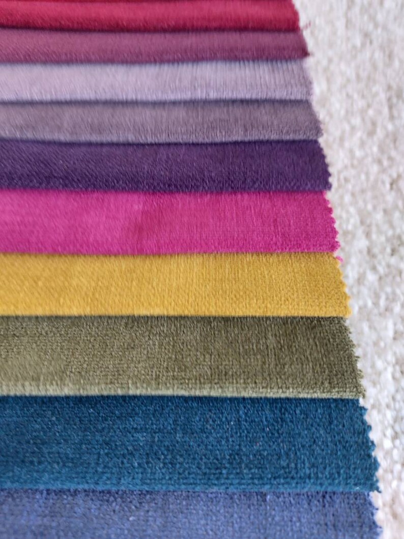 May include: A stack of fabric swatches in various shades of purple, pink, yellow, green, and blue. The swatches are arranged in a gradient from dark to light.