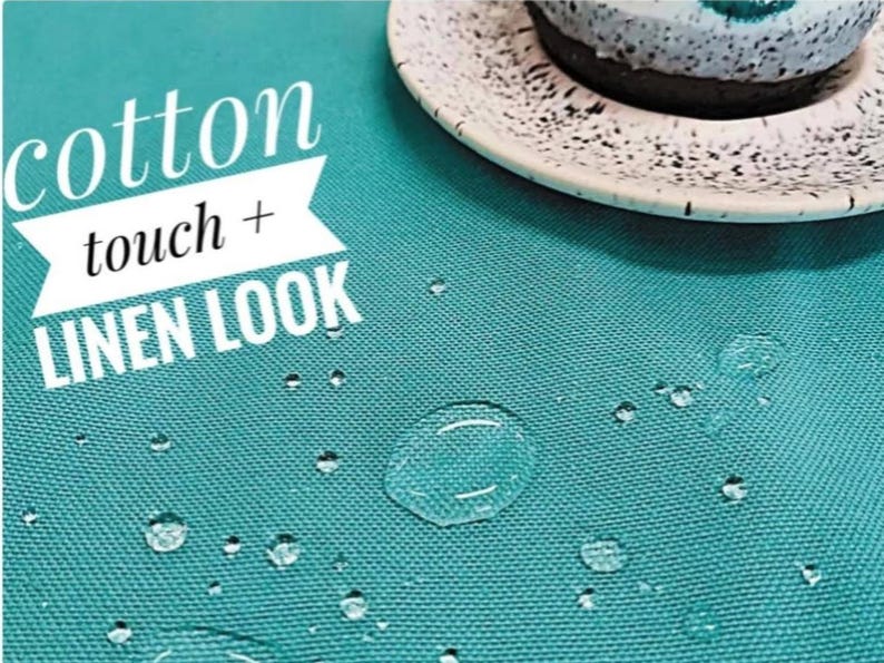 May include: A solid teal fabric with a woven texture featuring water droplets on the surface. The text "cotton touch + LINEN LOOK" is printed in white on the left side. A speckled white and black plate with a dark dessert sits in the corner.