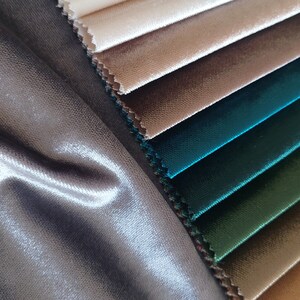 May include: A close-up of a fabric swatch book with a variety of colors and textures. The swatches are arranged in a fan shape, with the lightest colors at the top and the darkest colors at the bottom. The swatches are made of velvet and have a soft, luxurious feel.