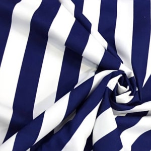 May include: White and navy blue striped fabric with a diagonal pattern. The fabric is folded and draped, showing the texture and color of the material.