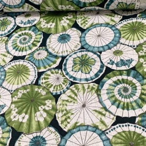 May include: A fabric with a repeating pattern of green, blue, and white umbrellas. The umbrellas are arranged in a random pattern on a dark blue background.