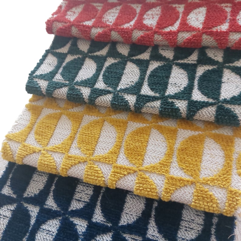 May include: Close-up of four fabric swatches in red, green, yellow, and navy blue. Each swatch features a repeating geometric pattern of half-circles and squares in white. The fabric has a textured, woven appearance.