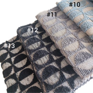 May include: Four kitchen towels with different geometric patterns. The towels are stacked on top of each other. The top towel is light blue with a white floral pattern. The second towel is gray with a white geometric pattern. The third towel is black and white with a geometric pattern. The bottom towel is black and white with a geometric pattern. The towels are labeled #10, #11, #12, and #13.