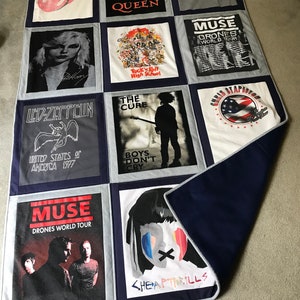 May include: A quilt made from various band t-shirts, including Queen, Muse, The Cure, Led Zeppelin, and Cheap Thrills. The quilt is made of a gray fabric with navy blue borders.