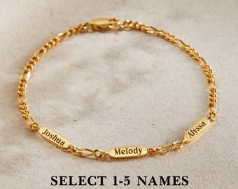 May include: A gold-toned chain bracelet featuring three small, elongated oval charms engraved with the names Joshua, Melody, and Alyssa. The bracelet includes a lobster claw clasp and the text SELECT 1-5 NAMES printed below the jewelry piece.