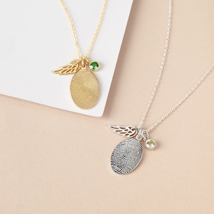 Two beautiful necklaces showcasing gold and silver fingerprint pendants, each with an angel wing and birthstone charm.