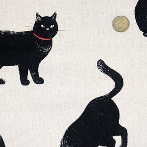 May include: Black and white fabric with a repeating pattern of black cats. The cats are in various poses, some are sitting, some are standing, and some are walking. The fabric has a subtle texture.
