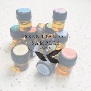 Op de afbeelding: Een verzameling kleine amberkleurige glazen flesjes met zwarte dopjes en etiketten. De flesjes zijn gevuld met etherische oliën en zijn gelabeld met verschillende namen. De flesjes zijn op een witte ondergrond in een stapel gelegd. De tekst "ESSENTIAL OIL SAMPLES 25 Drops" is op de afbeelding gedrukt.