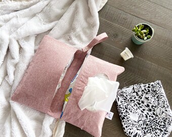 Può includere: Una custodia in tessuto color rosa polvere per salviette con chiusura a scatto e un'apertura centrale per erogare le salviette. La custodia è accompagnata da una piccola succulenta in un vaso color ottanio, un piccolo contenitore e un accessorio.